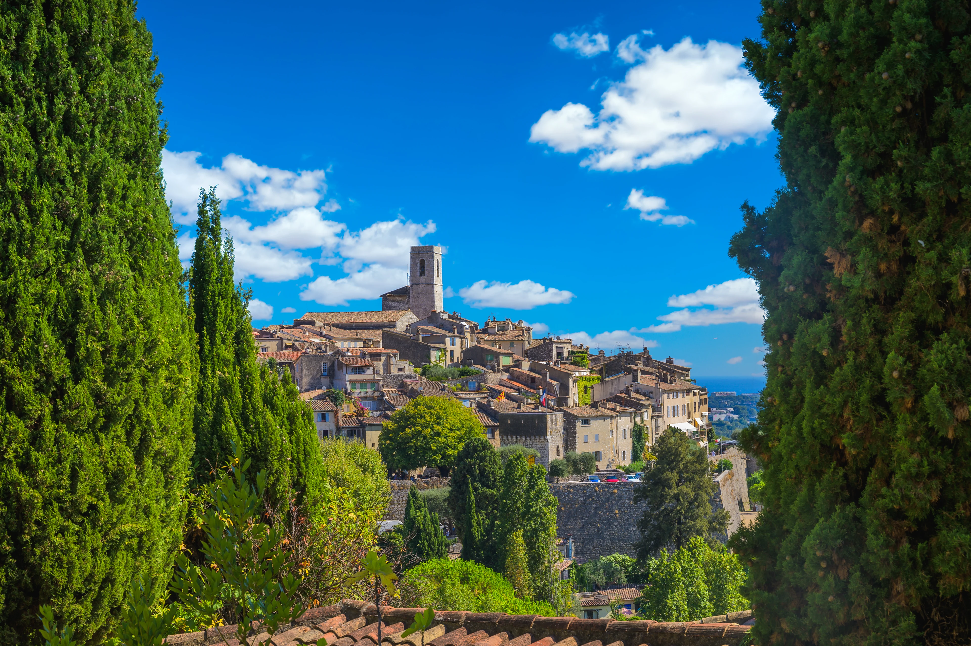 Saint-Paul-de-Vence på Franska rivieran med stenhus, cypresser och den historiska bykärnan omgiven av grönska under klarblå himmel.