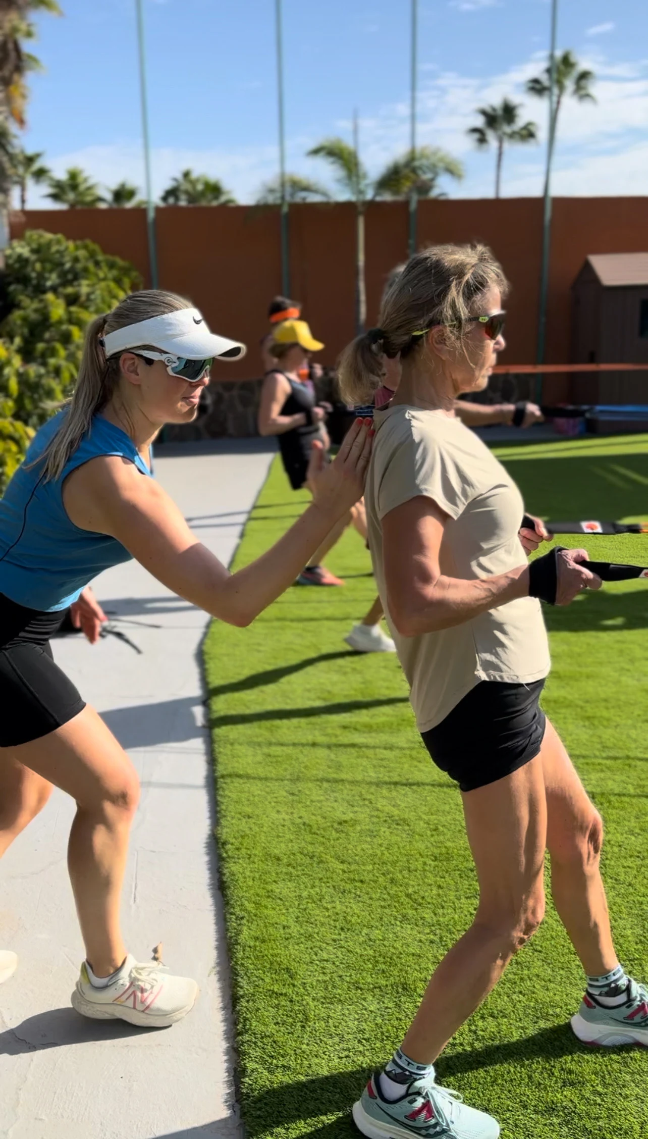 Instruktør som hjelper en deltaker som trener ute på en gressplen.