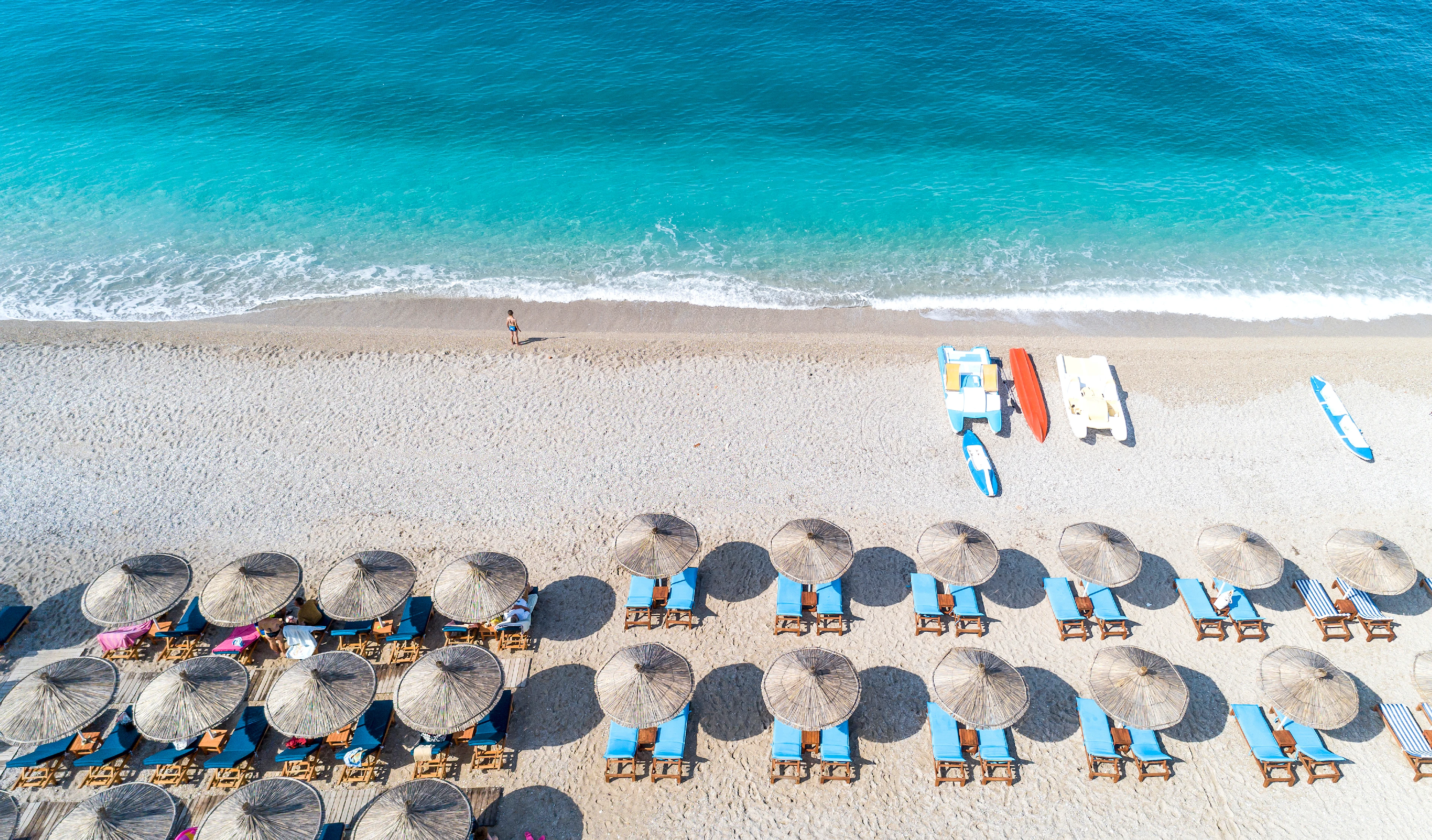 Zandstrand in Dhermi met turquoise water en ligbedden en parasols langs het strand