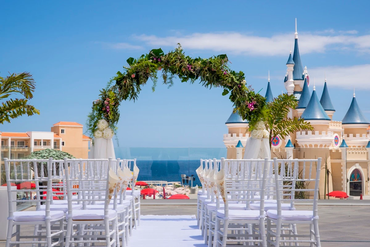 Bryllupsoppsetning på terrassen på hotell Bahia Principe Fantasia Tenerife. Med et eventyrlig prinsesseslott, blå himmel og blått hav i bakgrunnen.