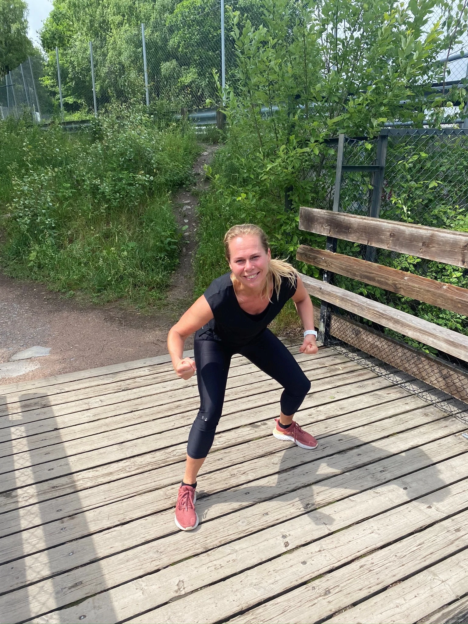 Marit står på en trebro i sort treningstøy