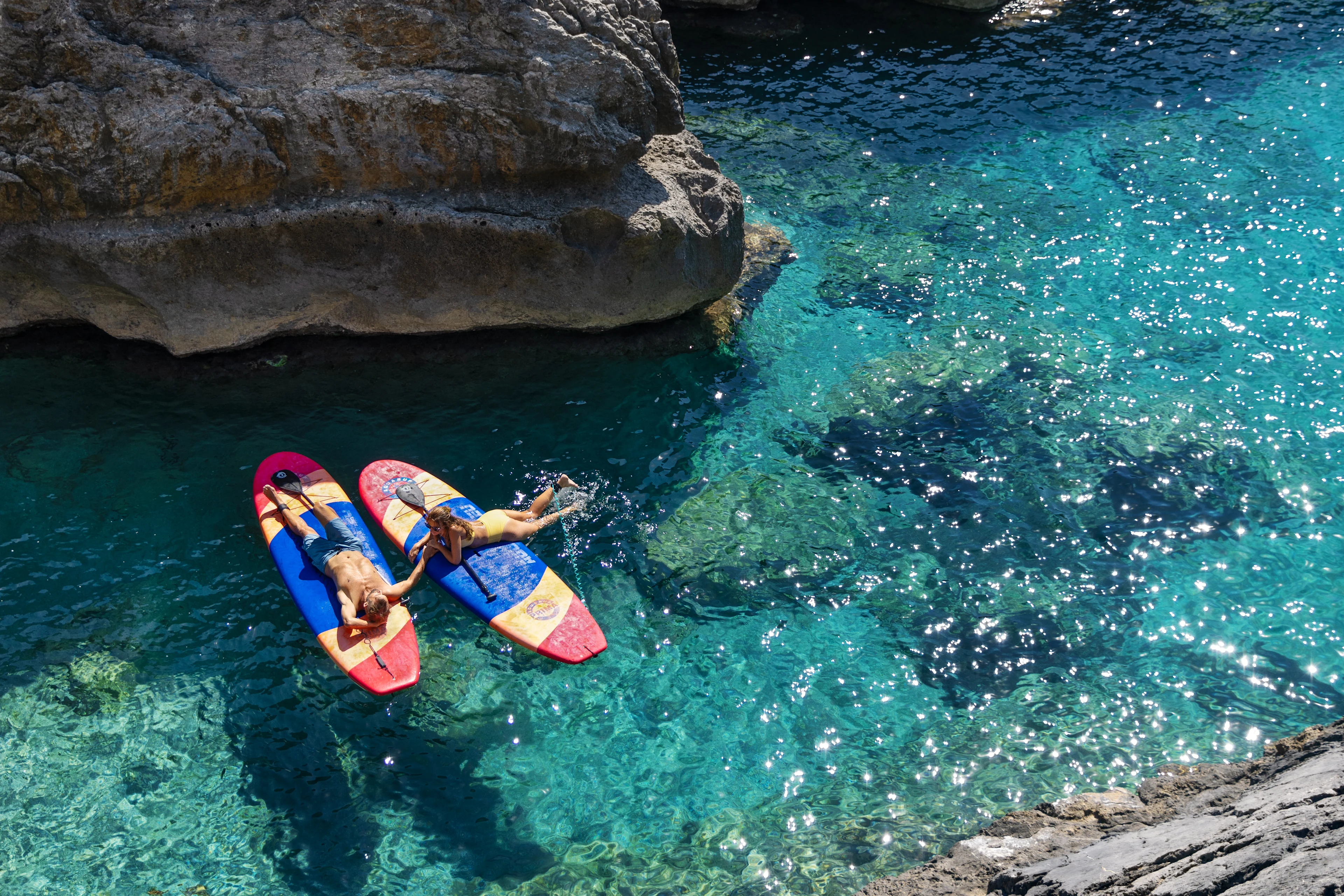 Ett par ligger på paddle boards i turkost vatten
