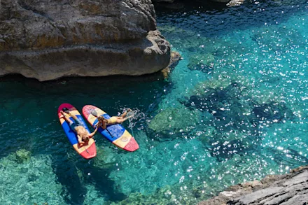 Ett par ligger på paddle boards i turkost vatten