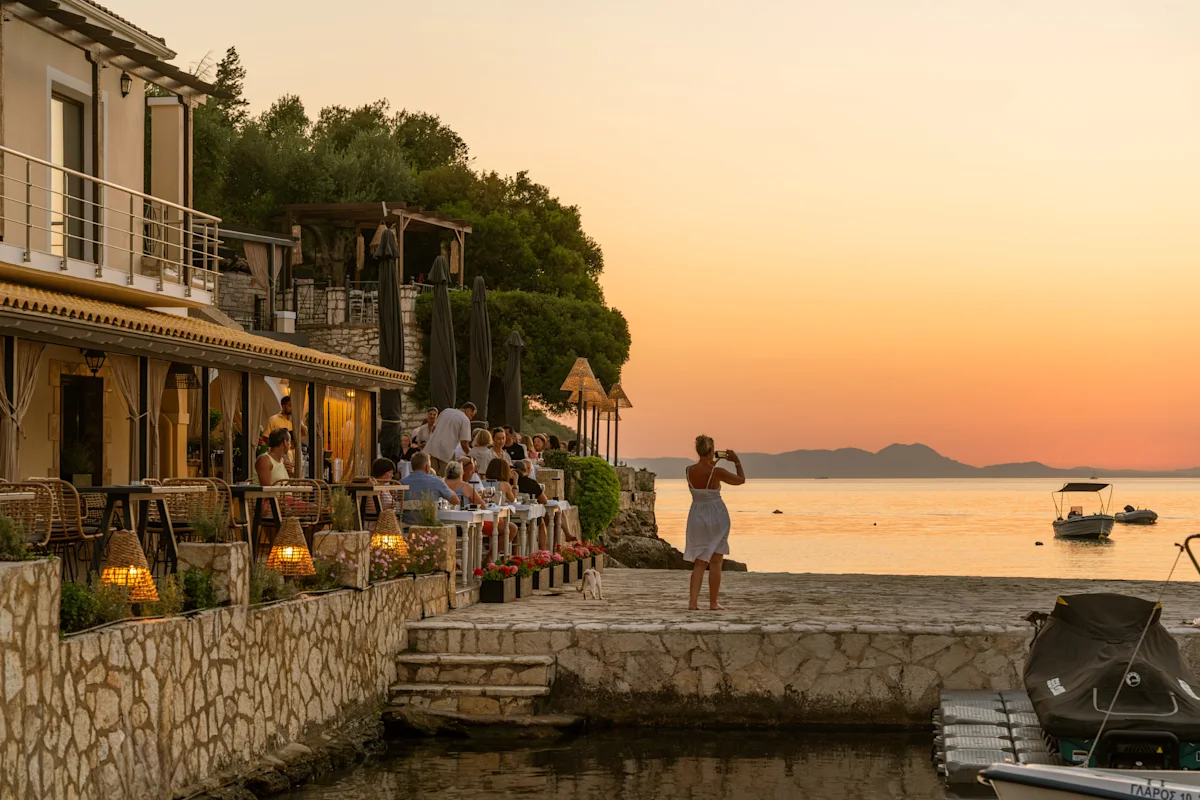 Tjej som fotograferar solnedgången över havet vid Filakas i Sivota