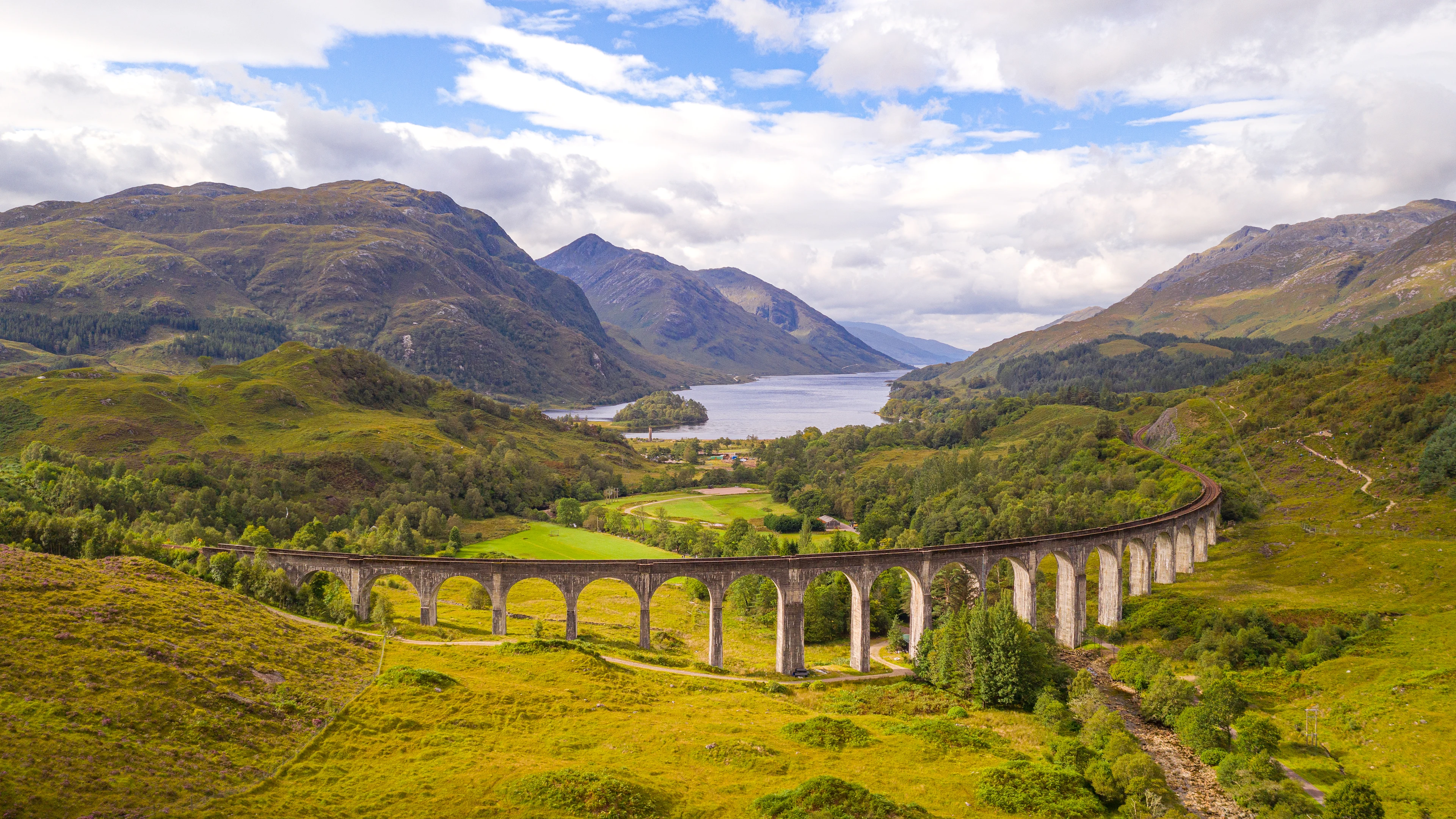 Glenfinnan-viadukten i Skottland, känd från Harry Potter, omgiven av gröna berg och dalar