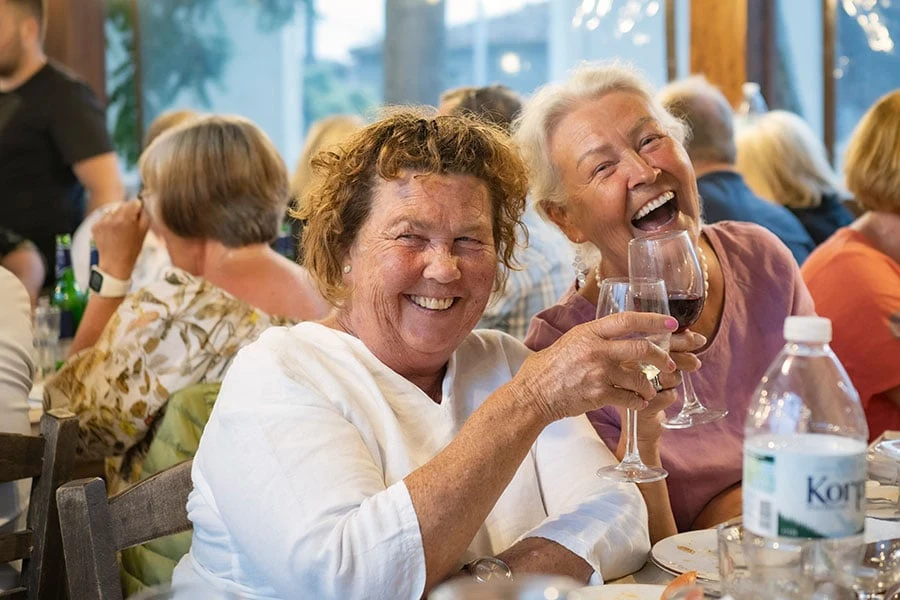 Två glada kvinnor som skålar med vin på Limnos