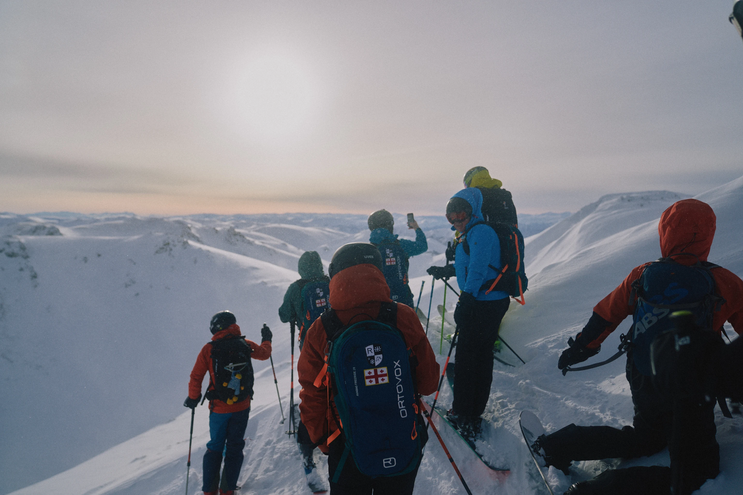 Skidåkare med ryggsäckar på en snötäckt bergsrygg i vinterlandskap