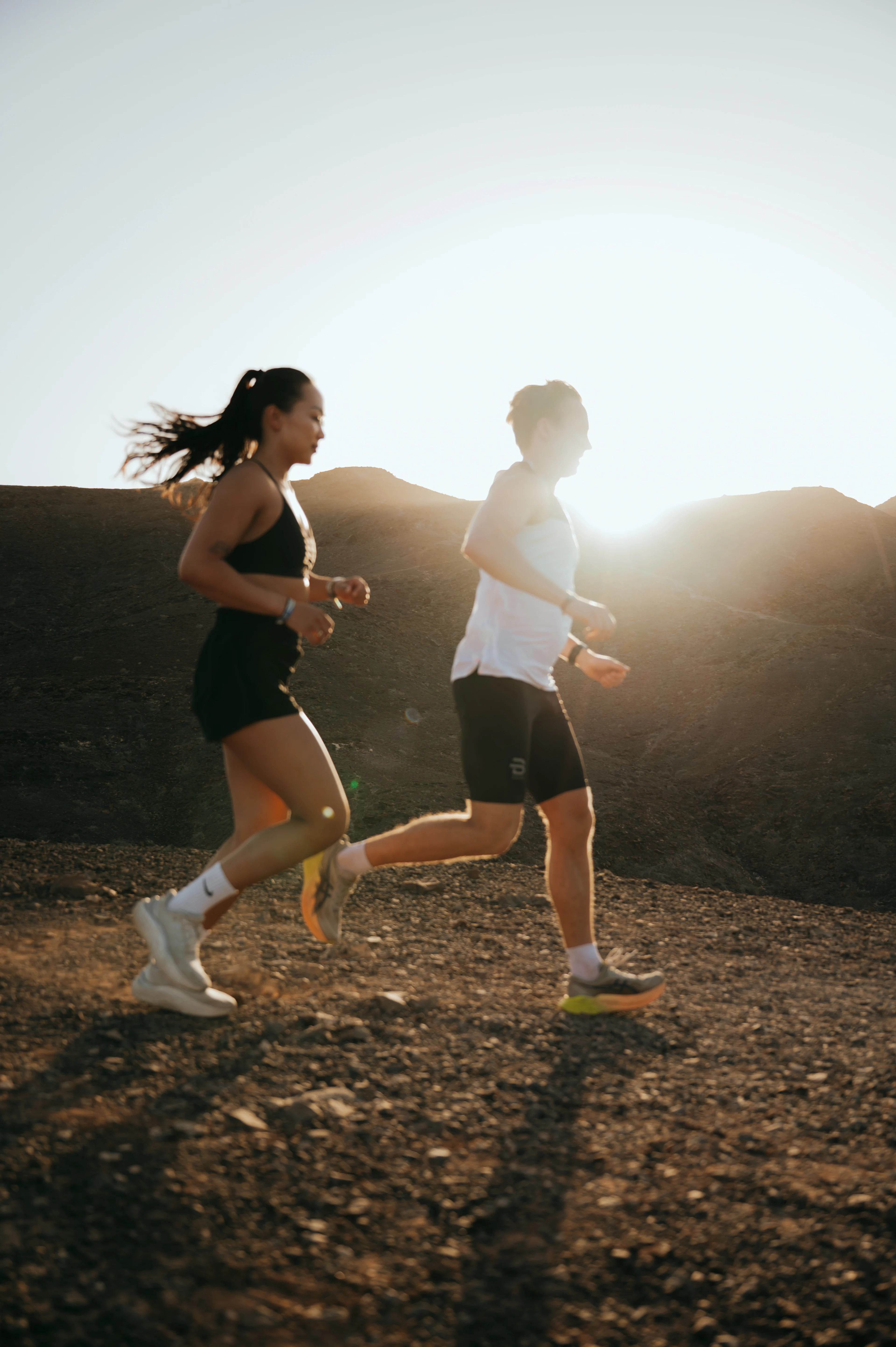 To personer jogger på en grusvei i et solfylt landskap