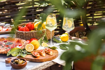 Ett uppdukat bord med drinkar, pizza och färgglada frukter och grönsaker