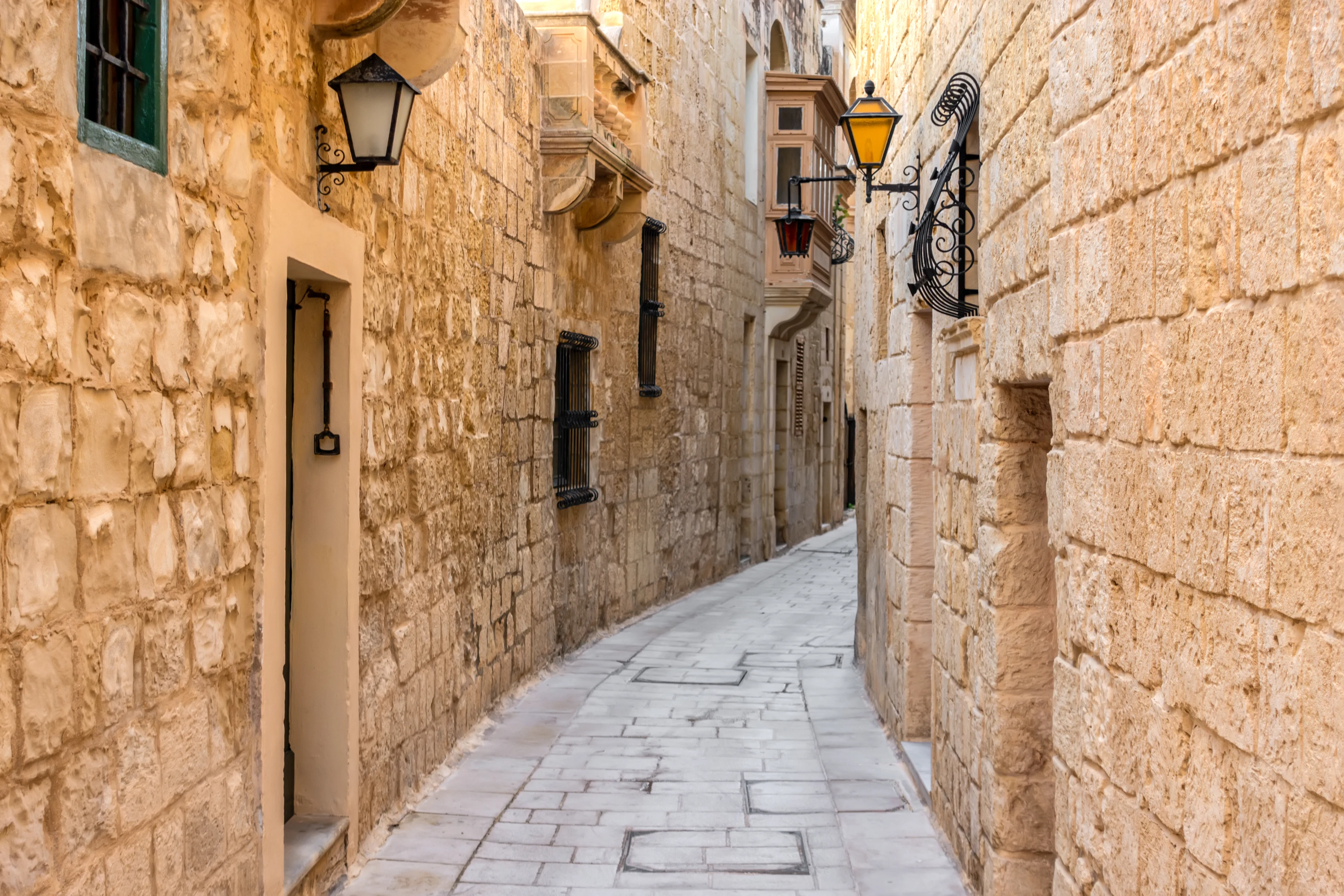 Smal gate i Mdina på Malta med de historiske kalksteinshusene og tradisjonelle lykter.
