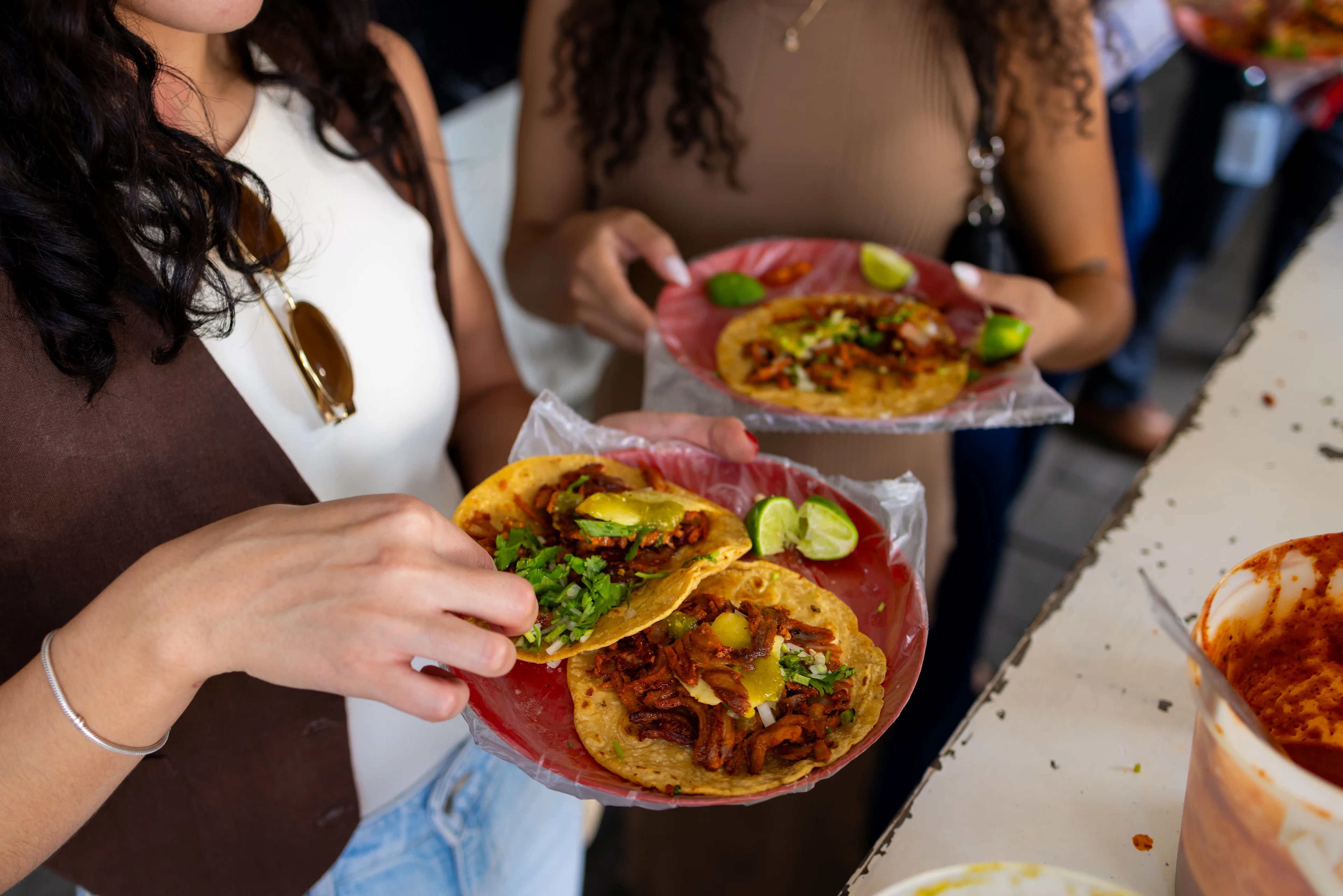 Två kvinnor äter tacos på en marknad i Mexiko