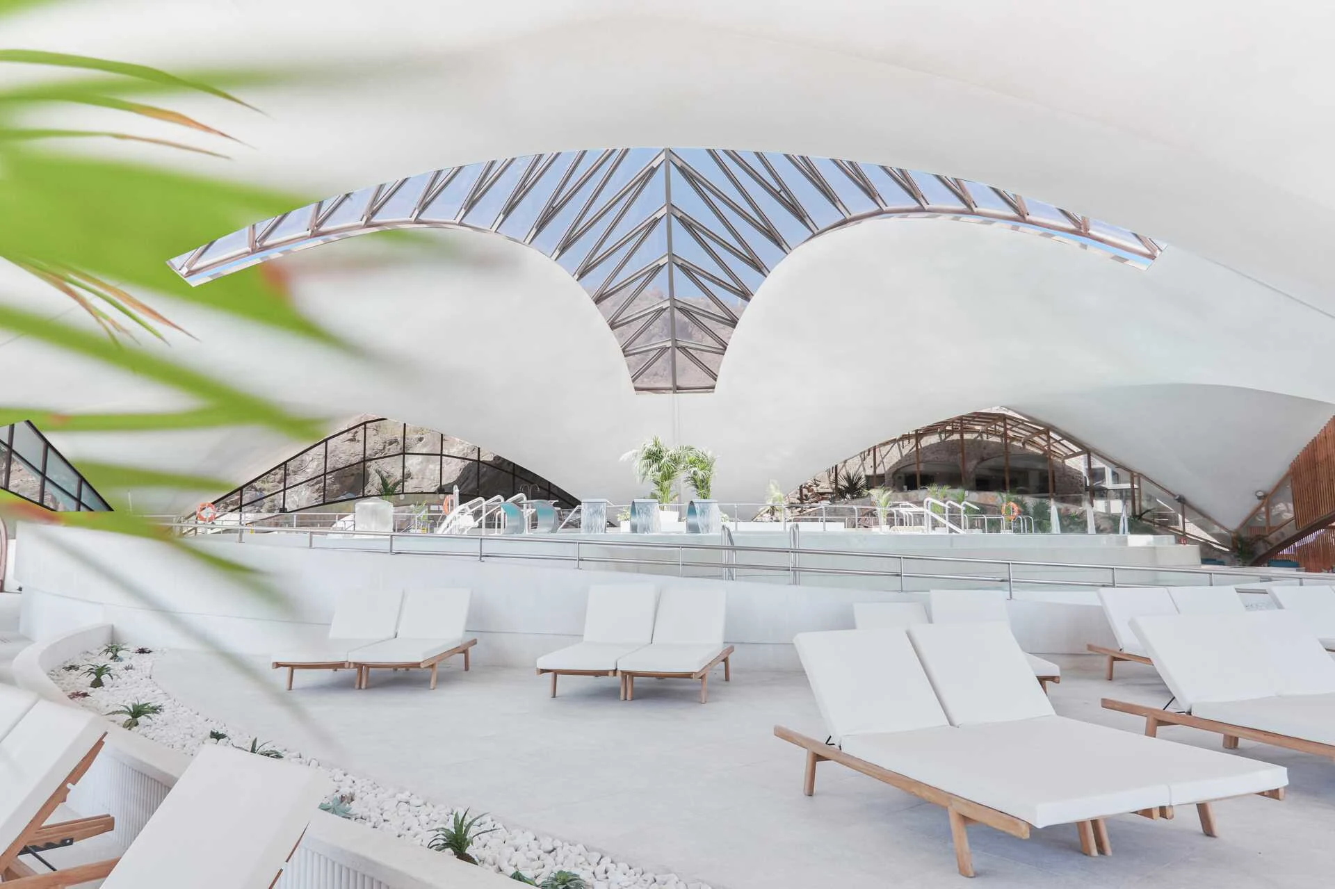 Bilde av hotell Gloria Palace i lyse farger. Bildet inneholder hvite/lyse solstoler, hvitt tak og blå himmel.