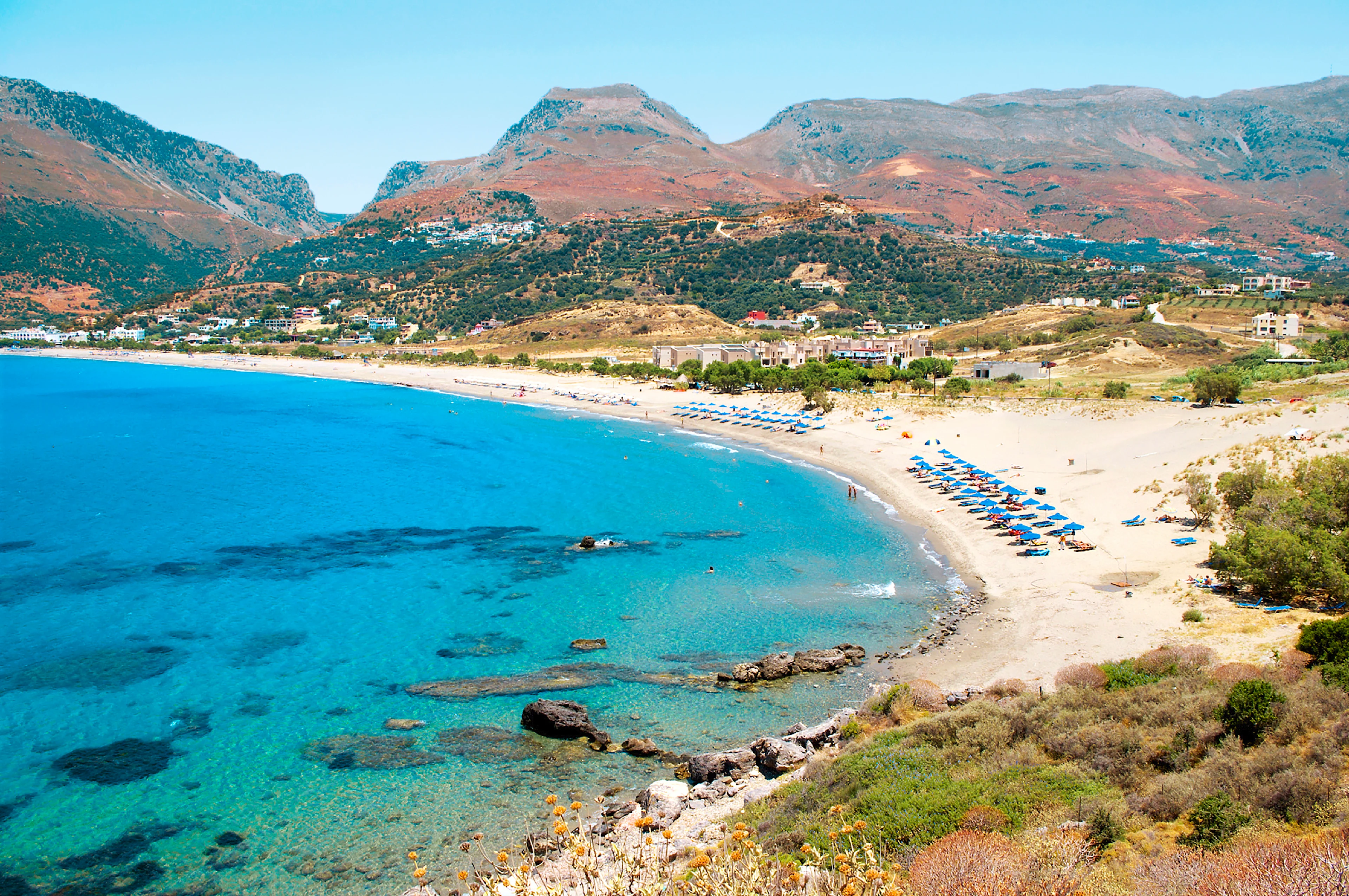 Stranden Plakias Beach med solsenger og parasoller med fjell i bakgrunnen