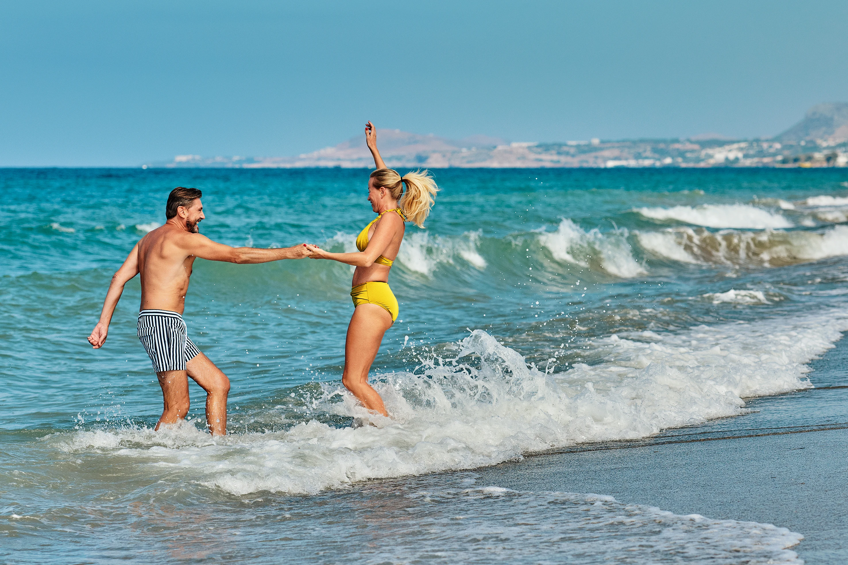 Et par danser på stranden i bølgerne