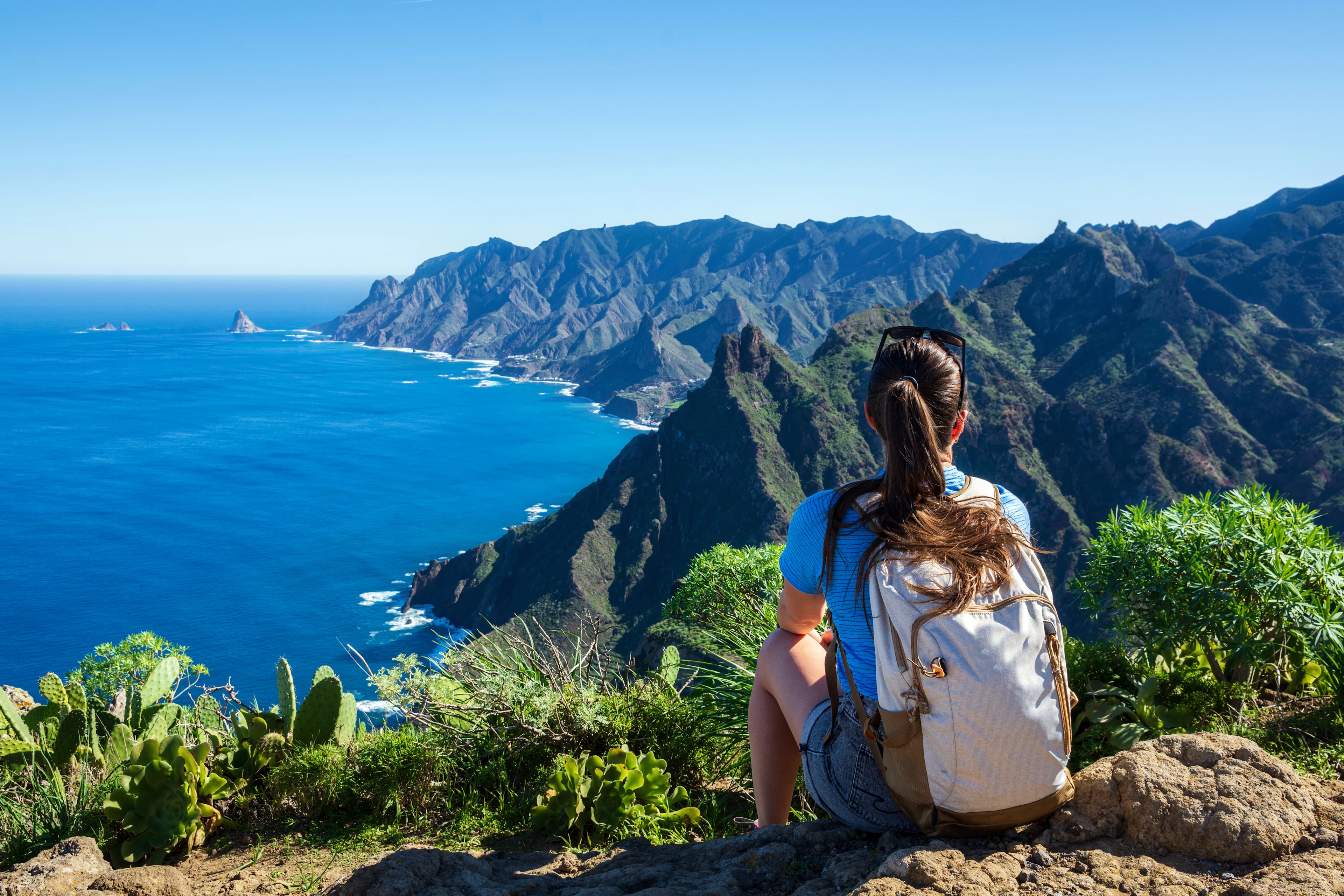 En kvinna som njuter av utsikten över Anagabergens gröna toppar och Atlantens blå vatten på Teneriffa