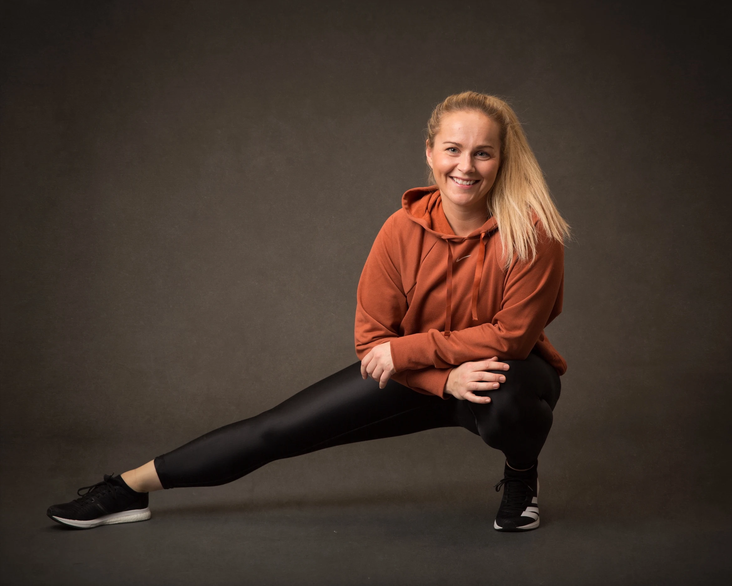 Ann Christin som står vendt mot kameraet og strekker et ben ikledd sorte tights og en rustrød hoodie.