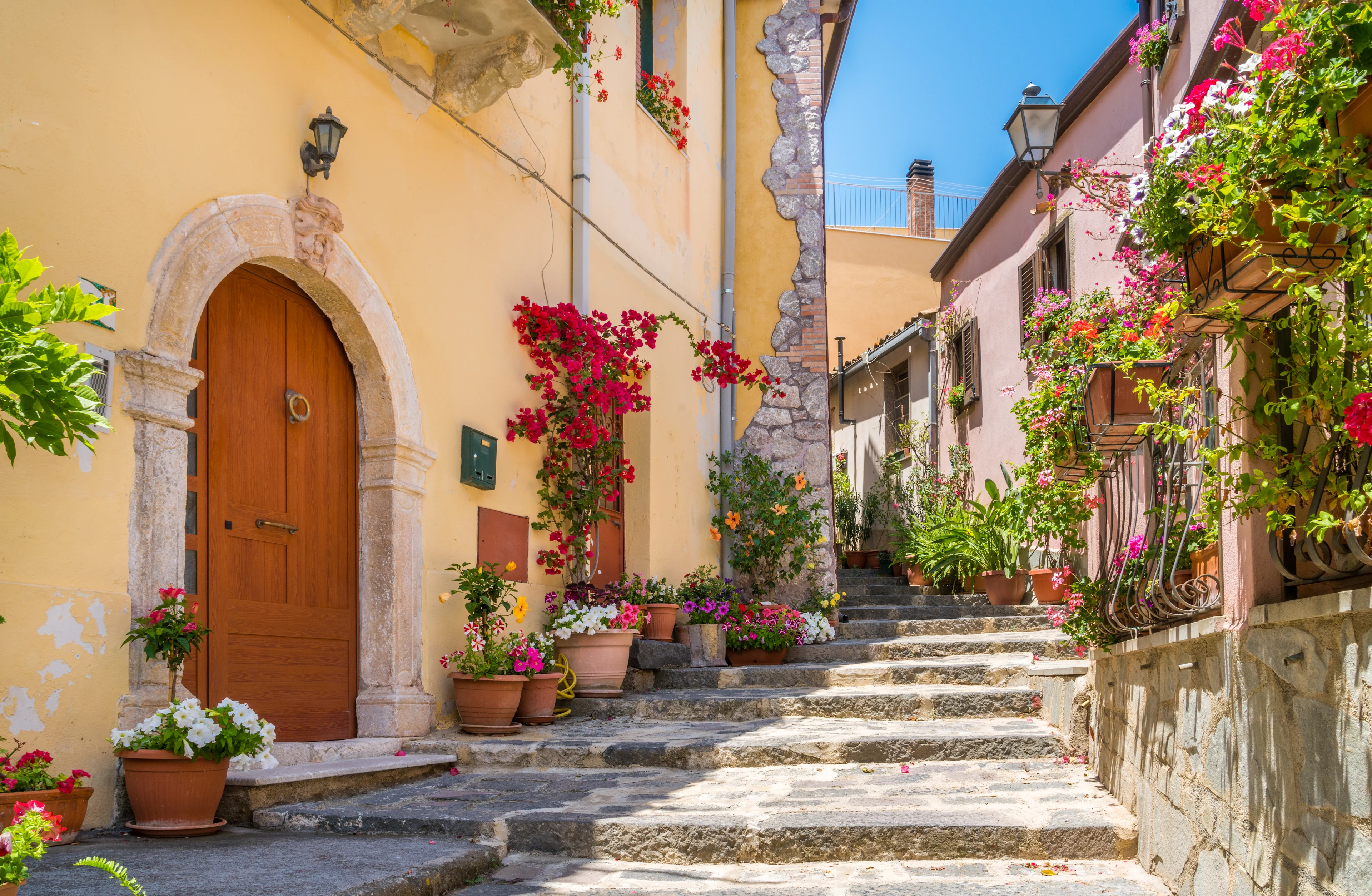 Pittoresk gränd i en siciliansk by med färgglada blommor och historisk bebyggelse