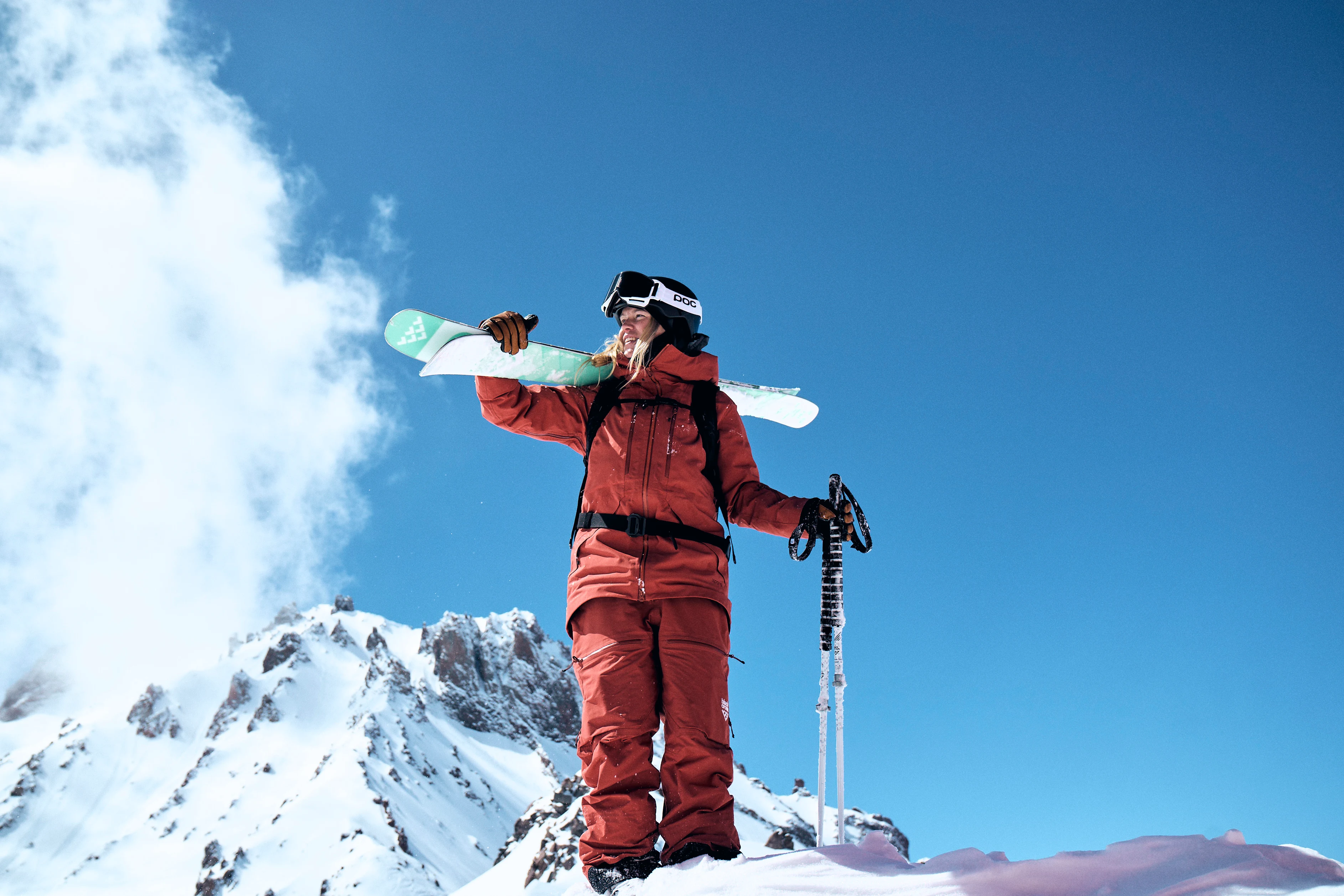 En ung tjej med skidutrustning och alptoppar i bakgrunden