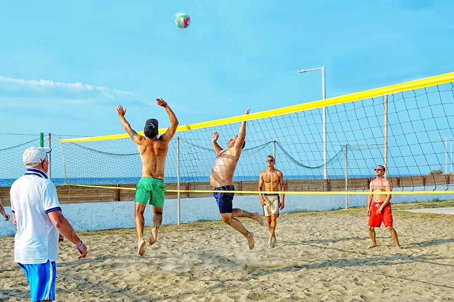 Vier mannen spelen beachvolleybal op het strand