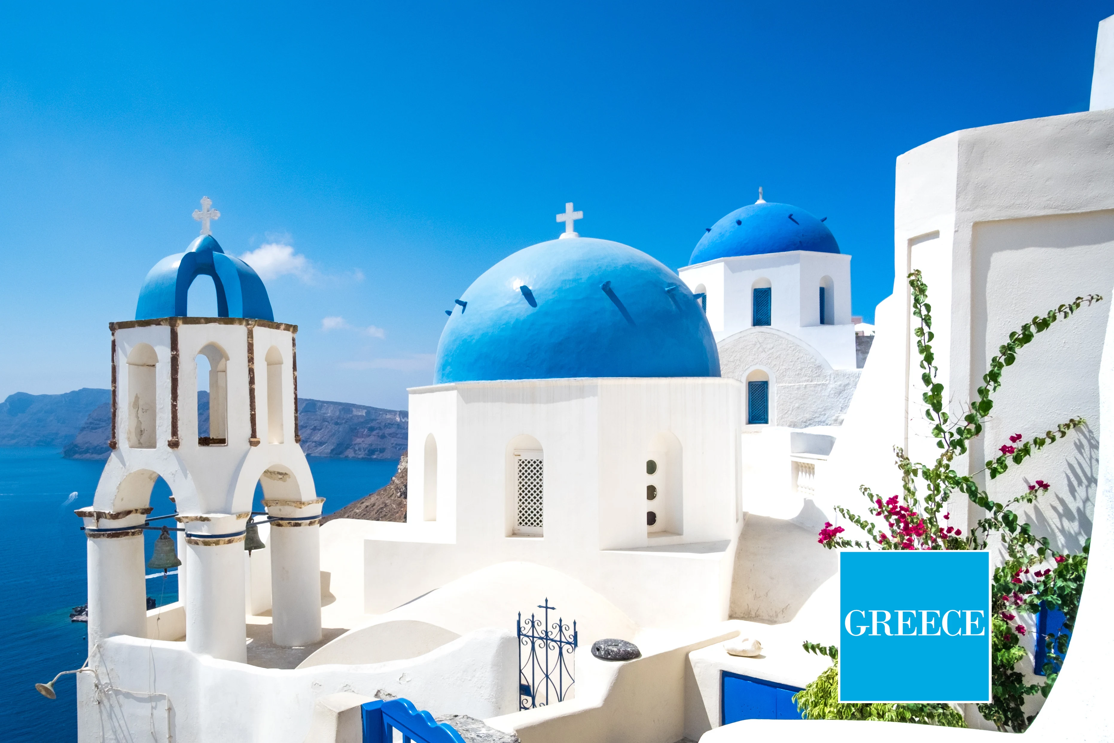  vita byggnader med blå kupoltak och hav i bakgrunden