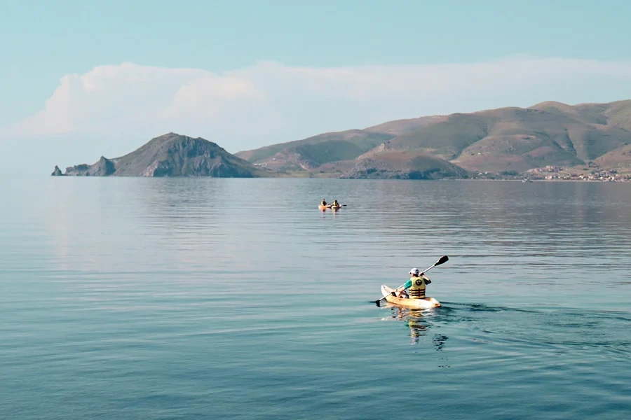 Kanoer ute på havet med fjell i bakgrunnen 