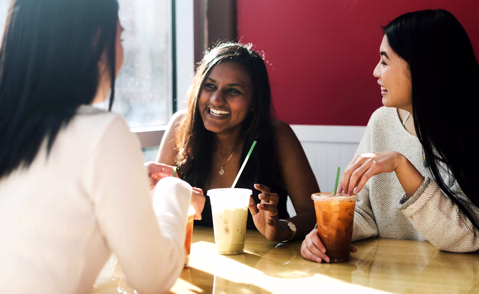 three-young-people-drinking-laughing-cafe