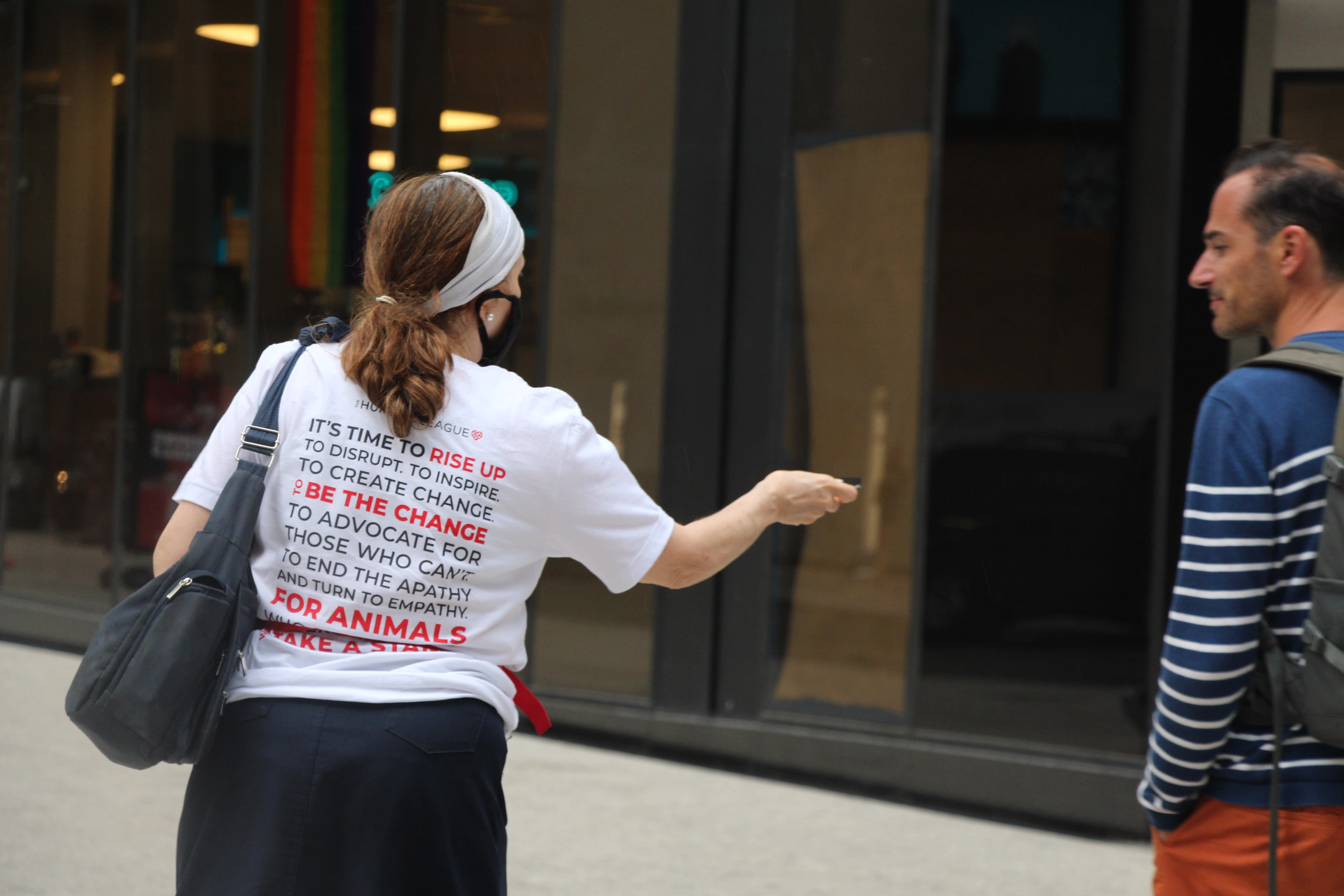 A protester giving a postcard to a passerby that explains why HelloFresh is failing animals