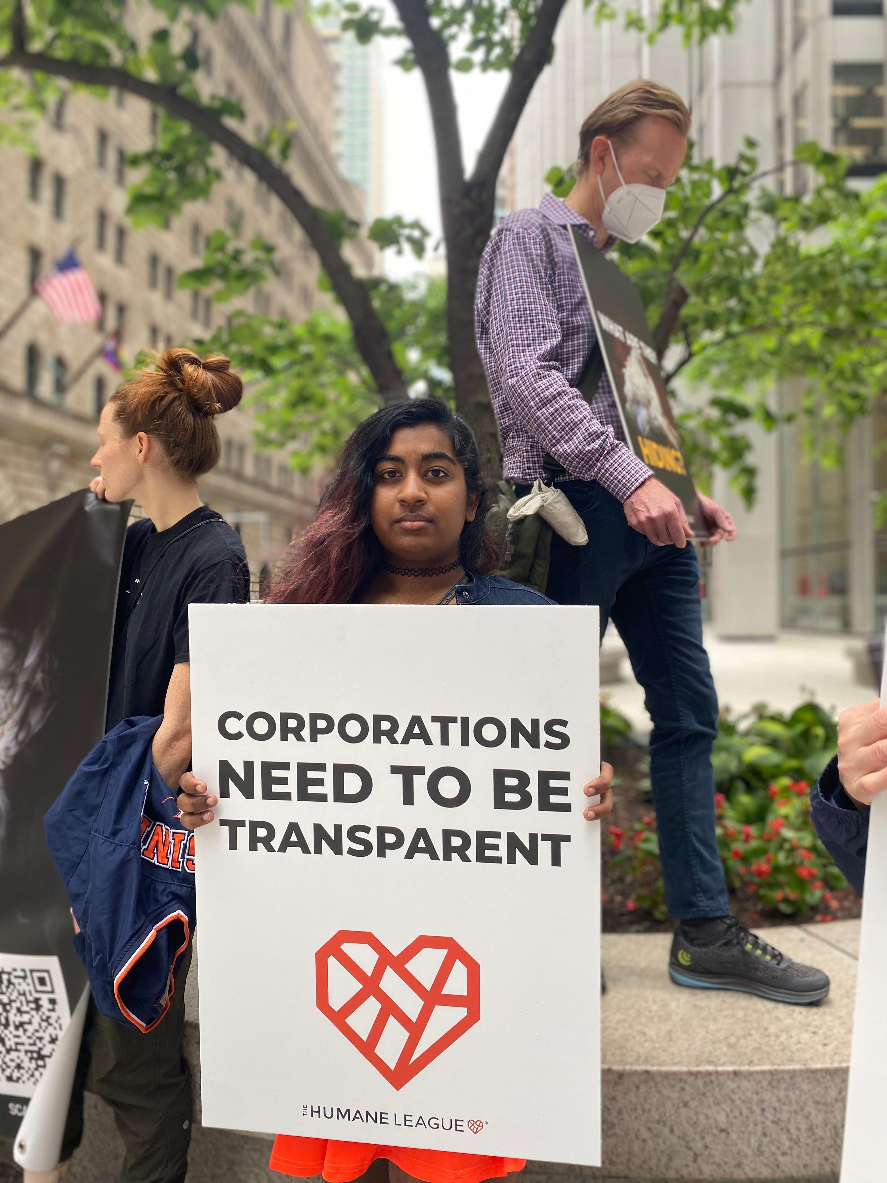 Protester holds a sign that reads: Corporations need to be transparent