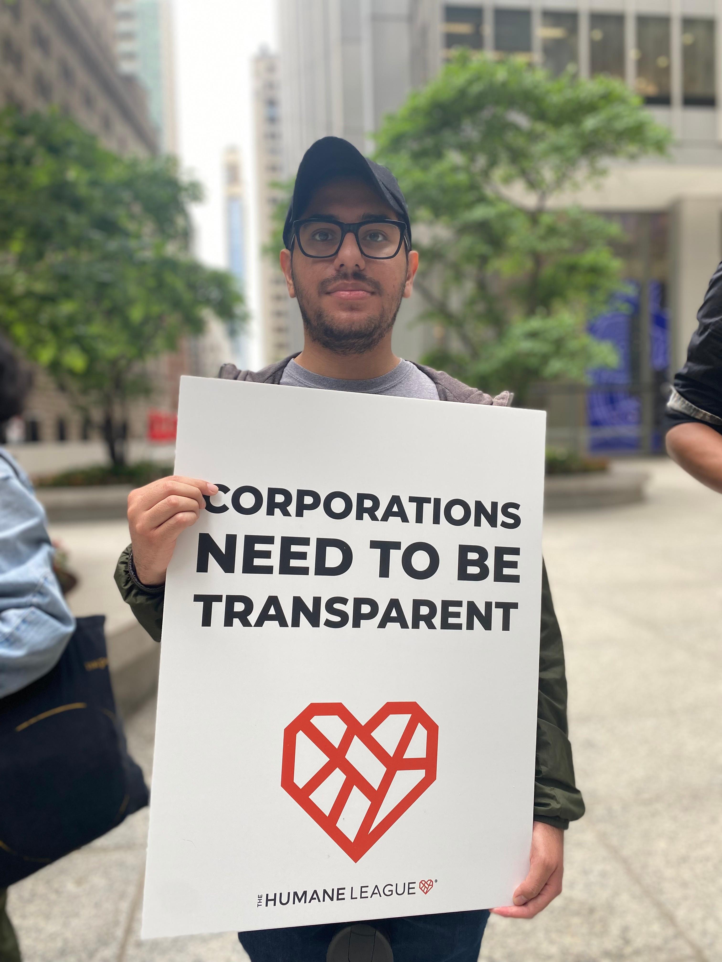 Protester holds a sign that reads: Corporations need to be transparent