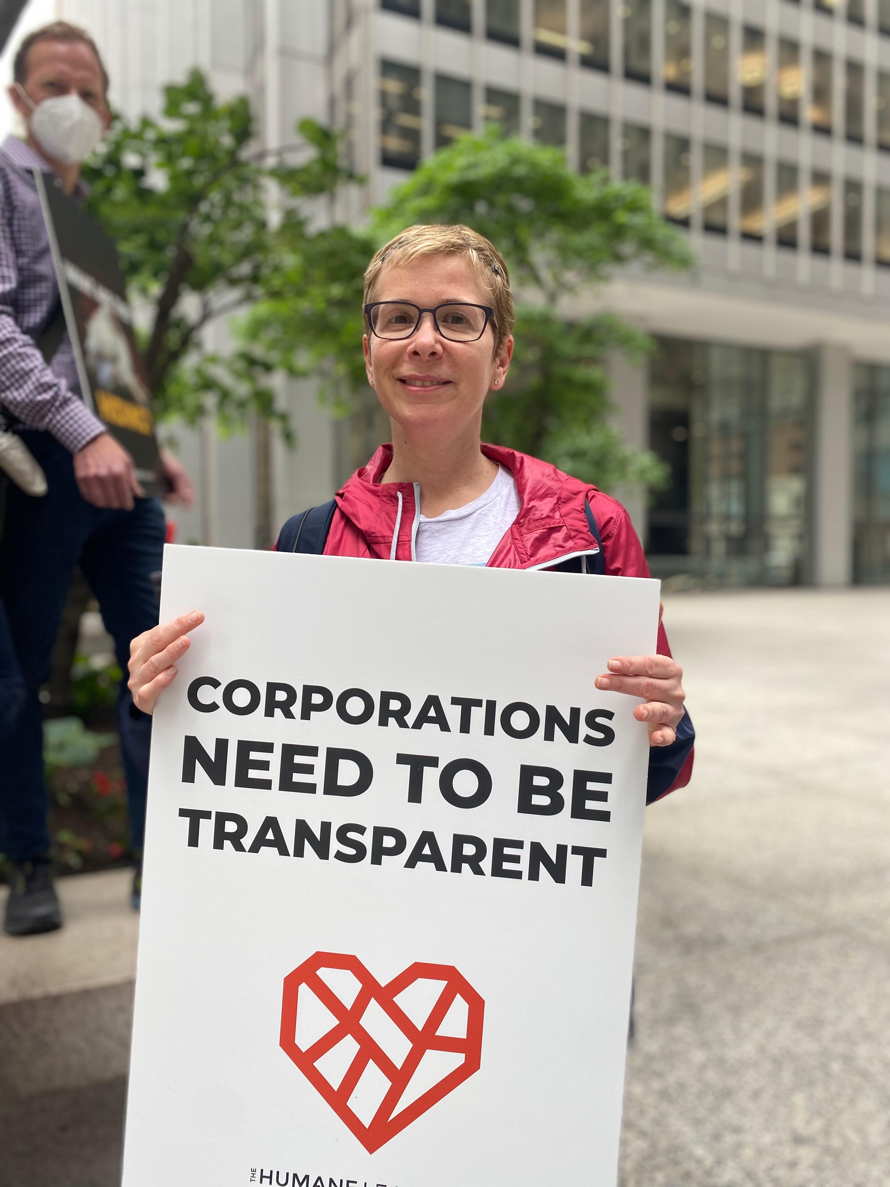 Protester holds a sign that reads: Corporations need to be transparent