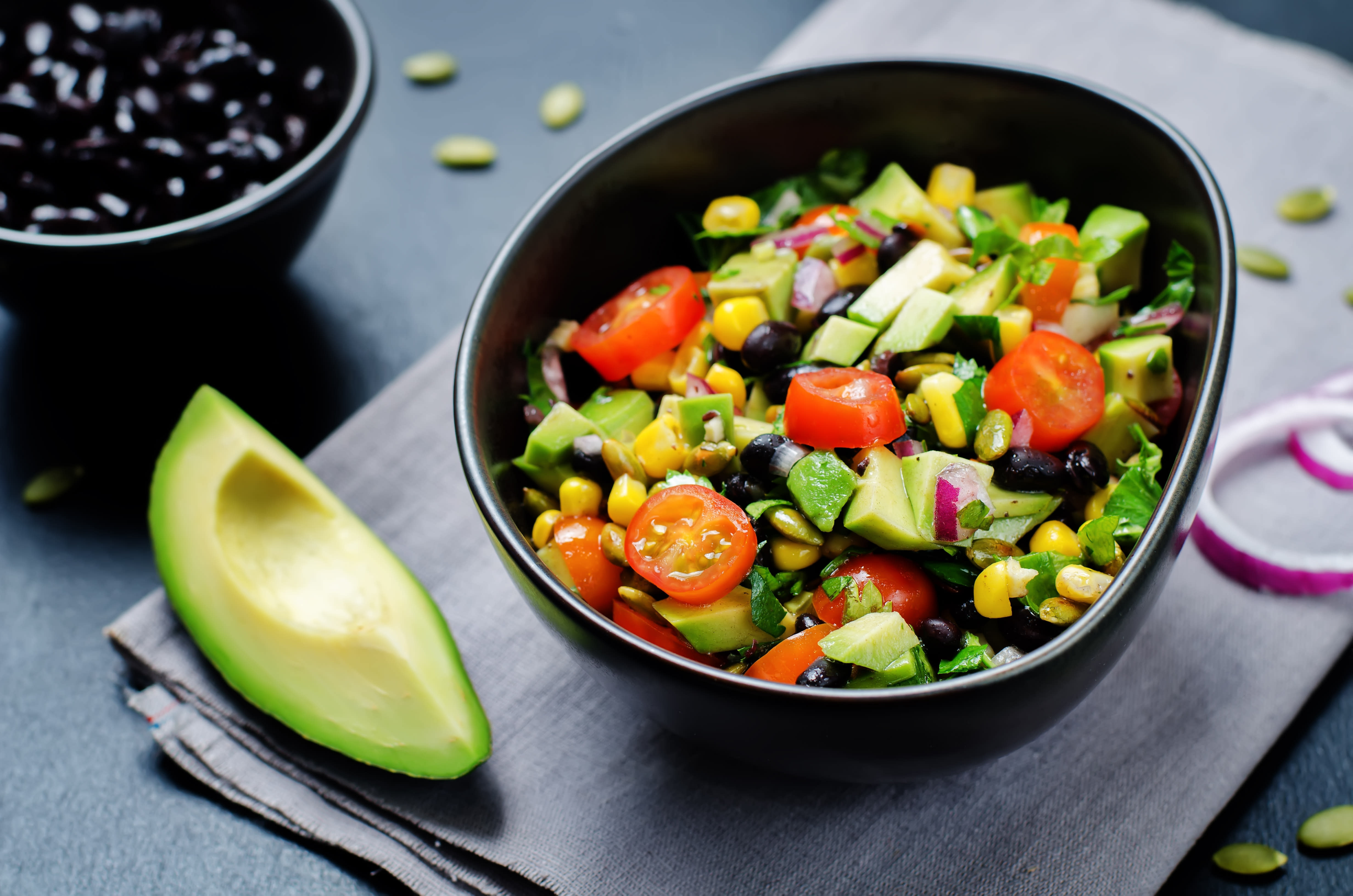 Bowl of chopped summer vegetables with an avocado and black beans