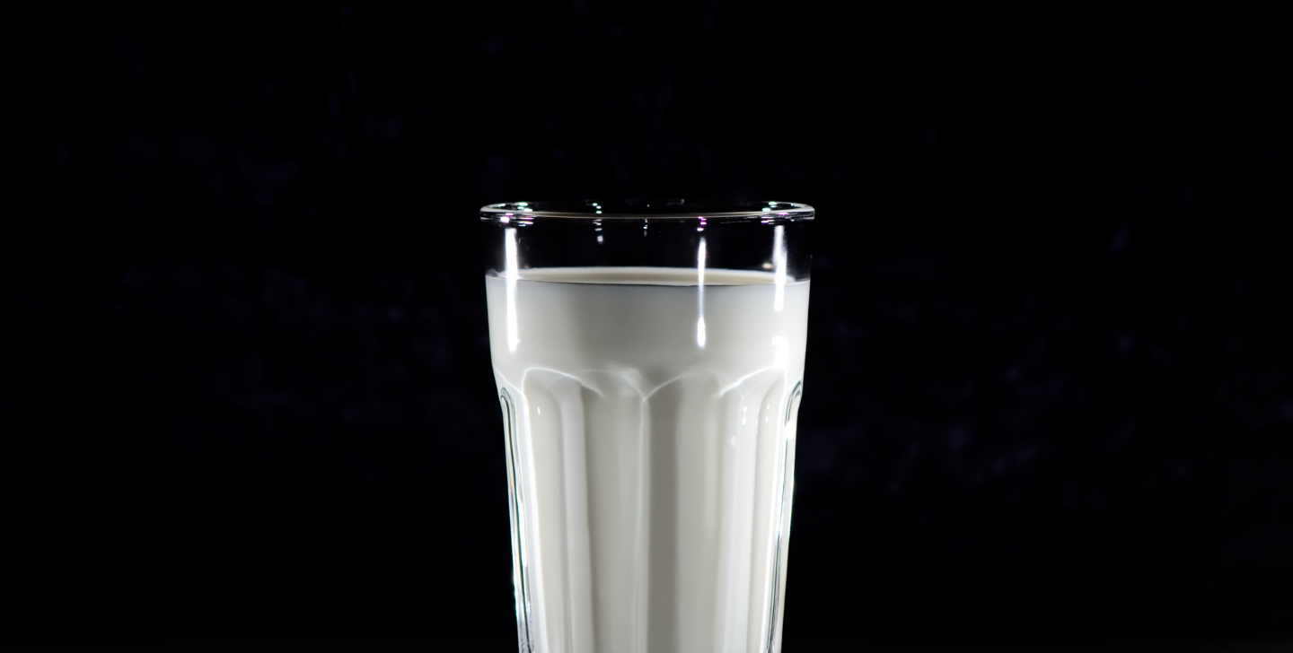 Vol glas met melk tegen een zwarte achtergrond