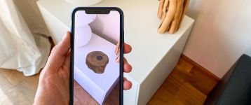 Smartphone shows an augmented reality image of a wooden object on top of a white surface