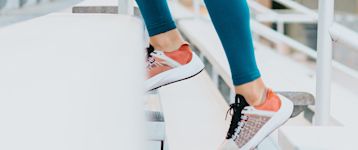 A pair of legs in sneakers stepping on stairs