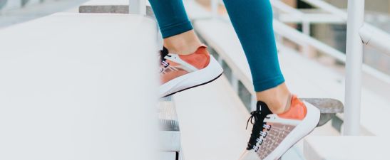 A pair of legs in sneakers stepping on stairs