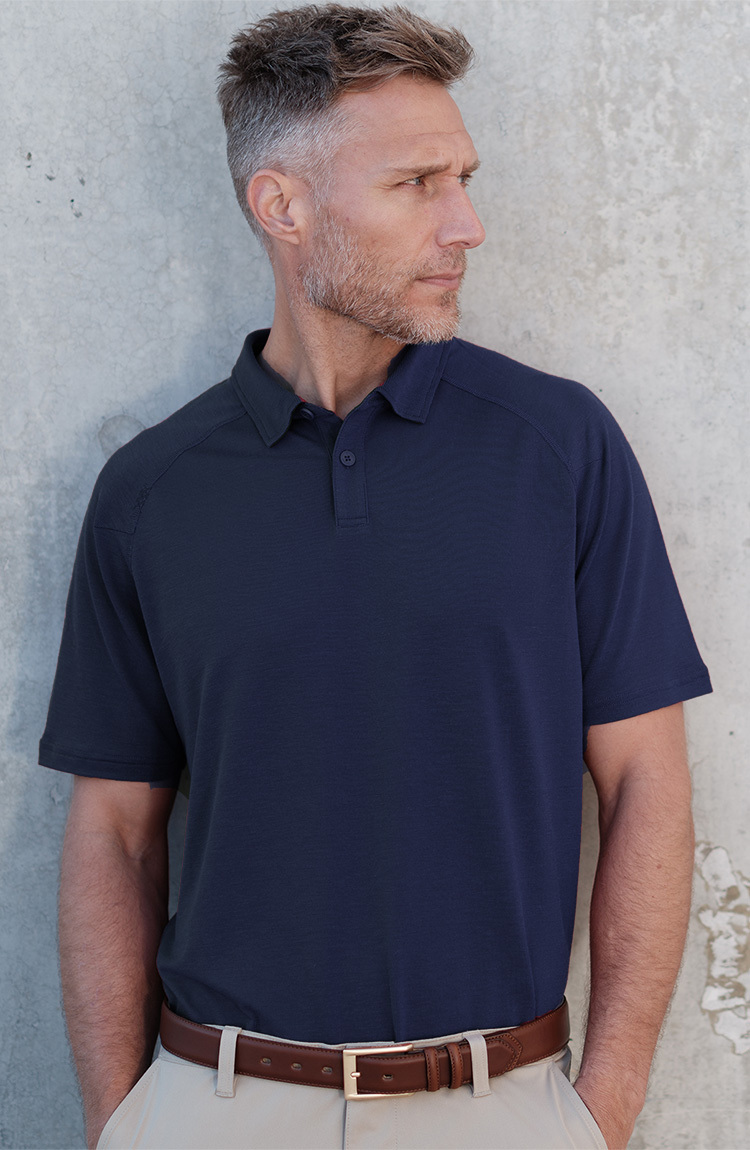 Man standing against a wall, Blue Delta Pique Polo 