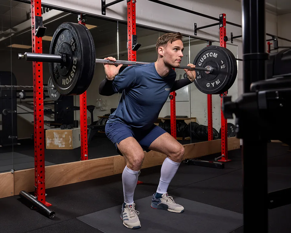 Billede 2 - træningsunivers - mand squatter i fitnesscenter