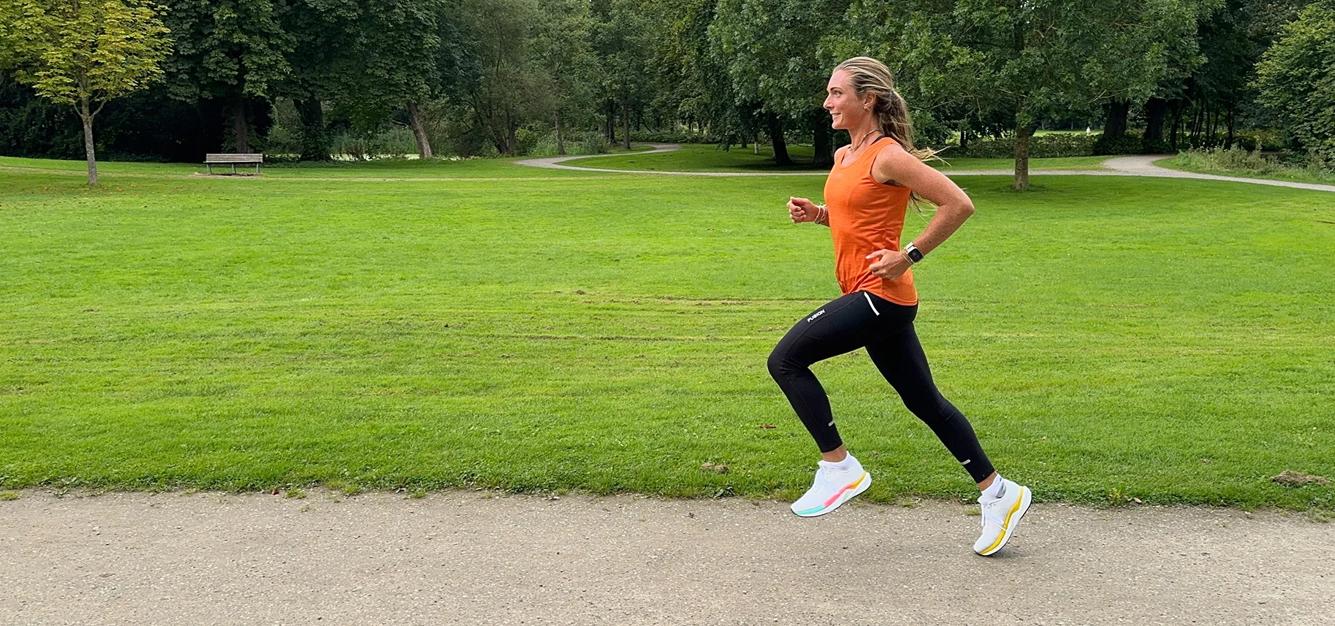 Topbillede kvinde i orange top løber på sti