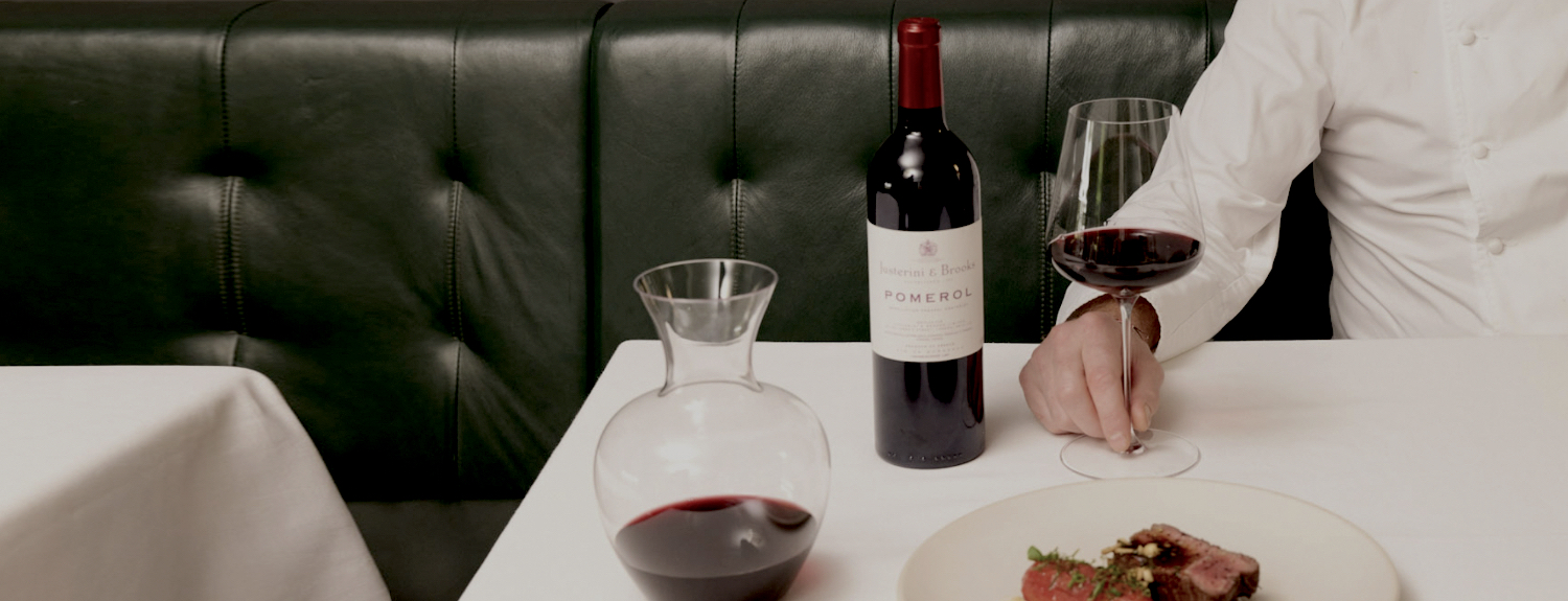 Man having dinner in a restaurant with a glass and bottle of justerinis red wine