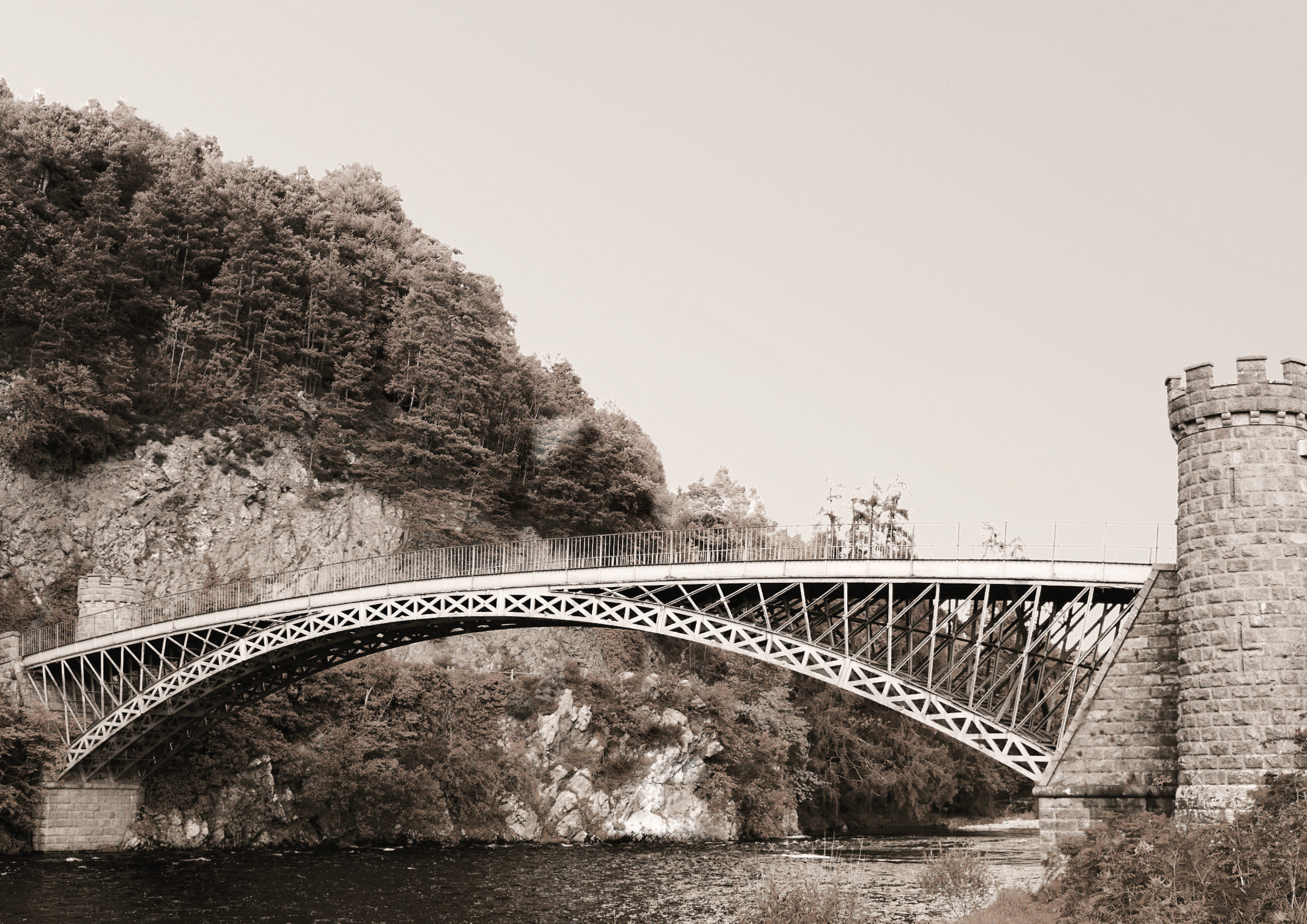 bridge over a river with a tower on one side and a tree on the other