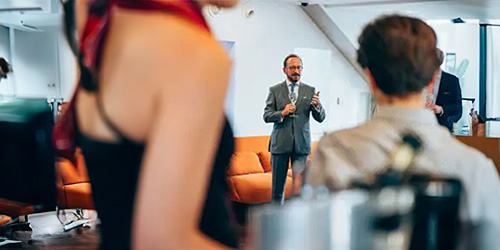 A person in a suit talking to a group of people