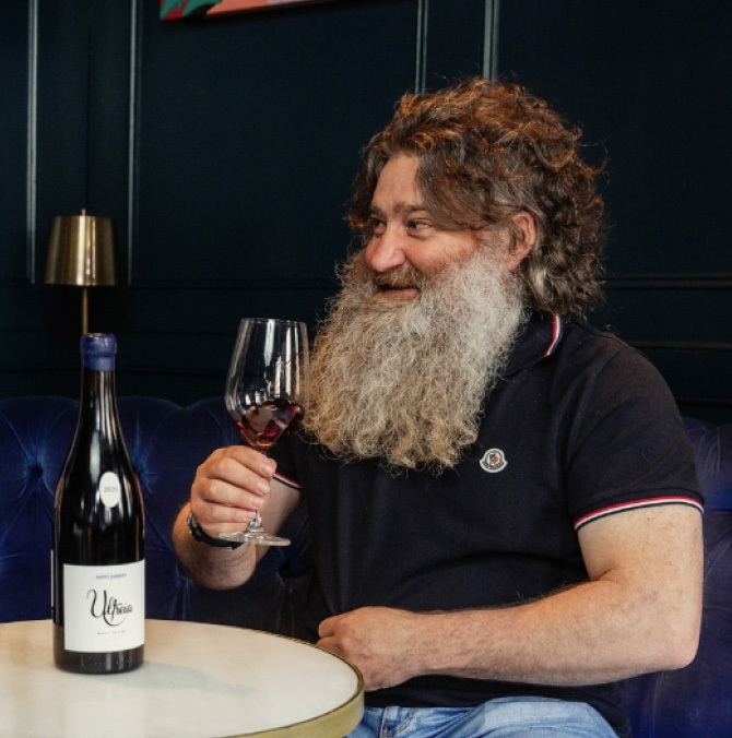 Raúl Pérez sitting on a table drinking a glass of wine