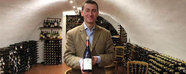 man in a wine cellar holding a bottle