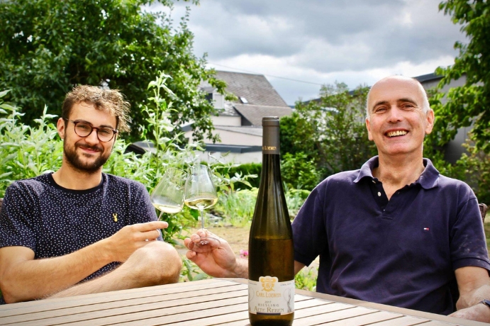 Two people outside drinking wine at a table. Carl Loewen