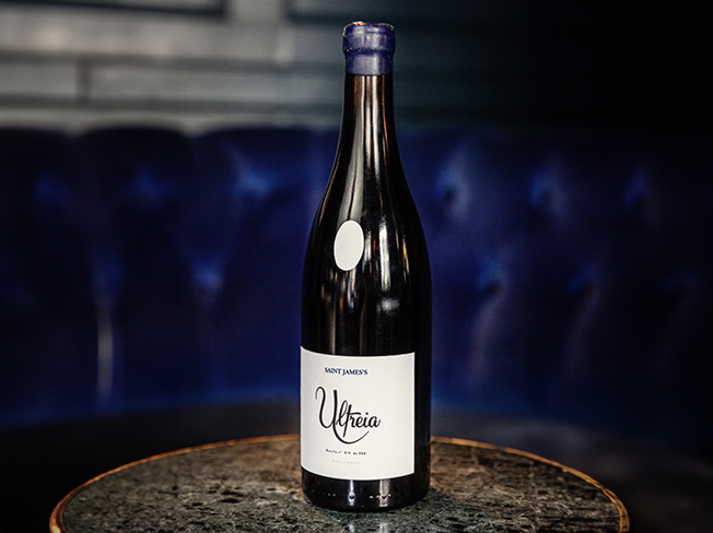 A bottle of Ulteria, Raul Perez on a table beside a blue sofa