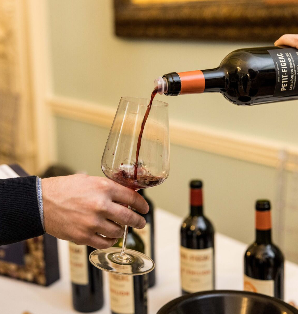 A person pouring red wine into a glass