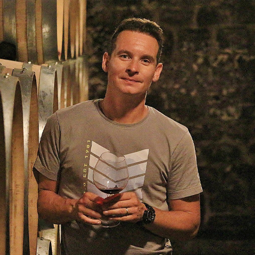 Robert Groffier holding a glass of red wine