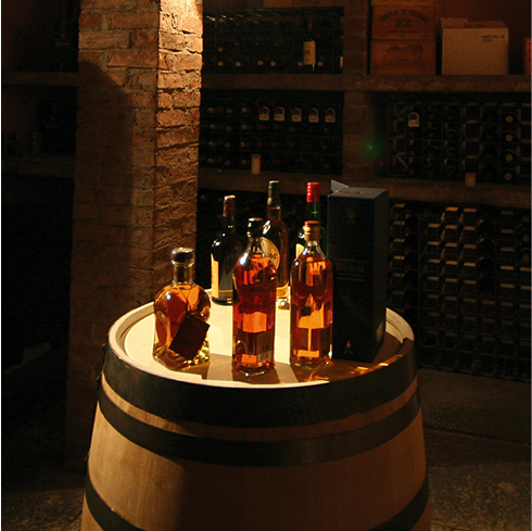 A group of whisky bottles on top of a cask in a store room