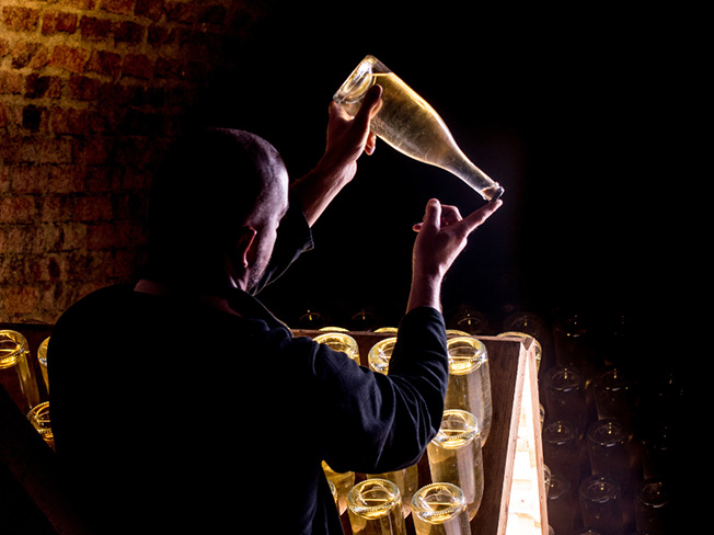 A person testing Champagne bottles in a wine cellar