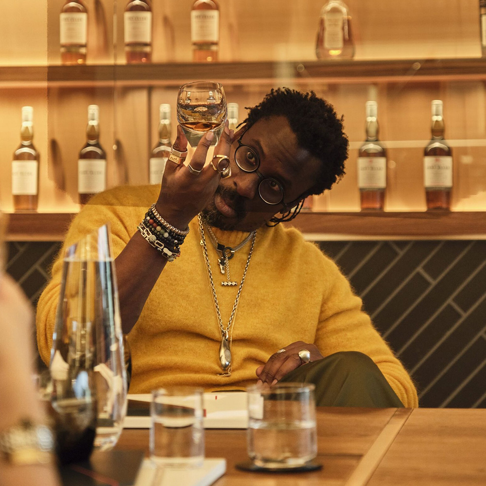 Ini Archibong in a room sitting with a glass of whisky